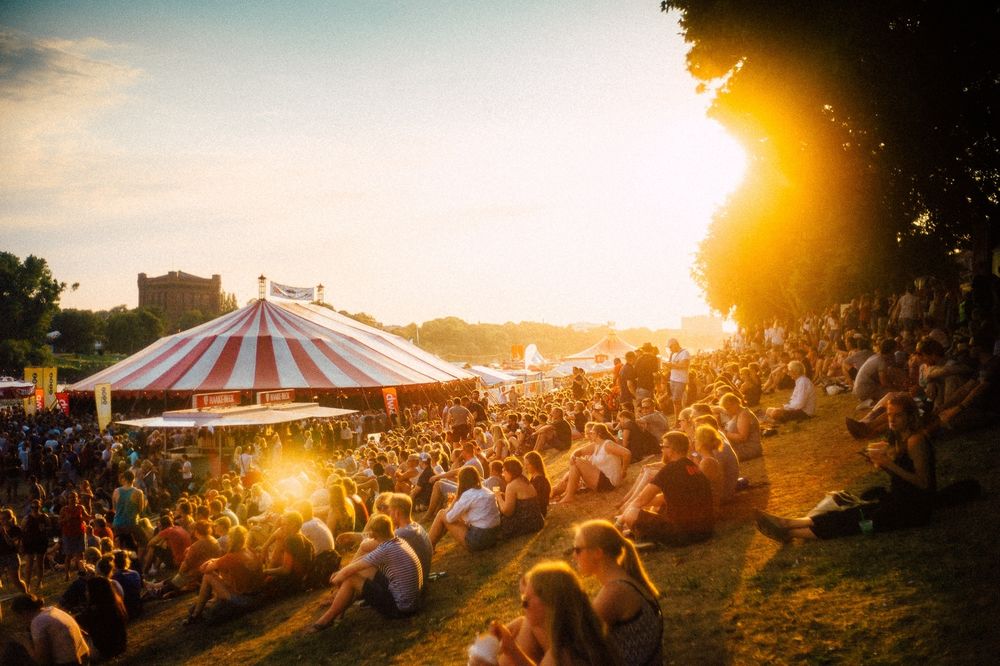 Menschen sitzen vor einem Zelt bei dem Sonnenuntergang - 